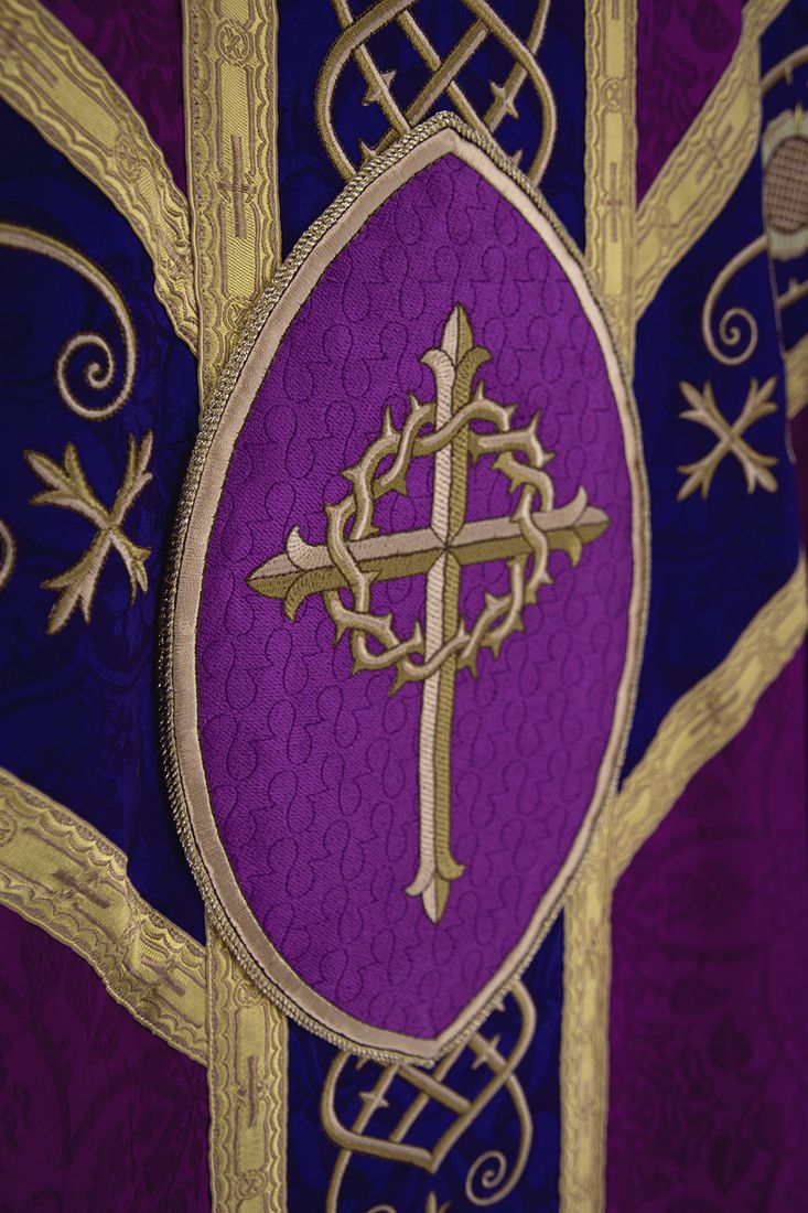 A gold cross wreathed in thorns in a vesica on a violet and purple chasuble