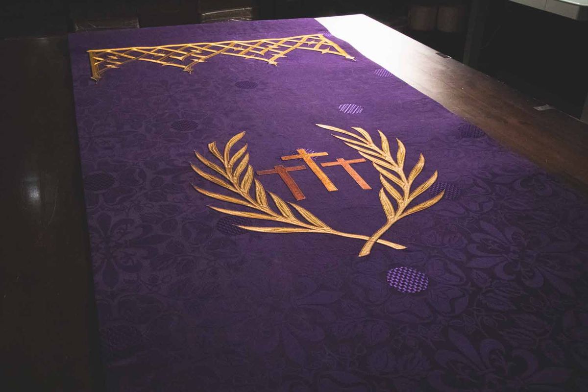 Palm branches and three crosses on a violet frontal under a gold lattice border