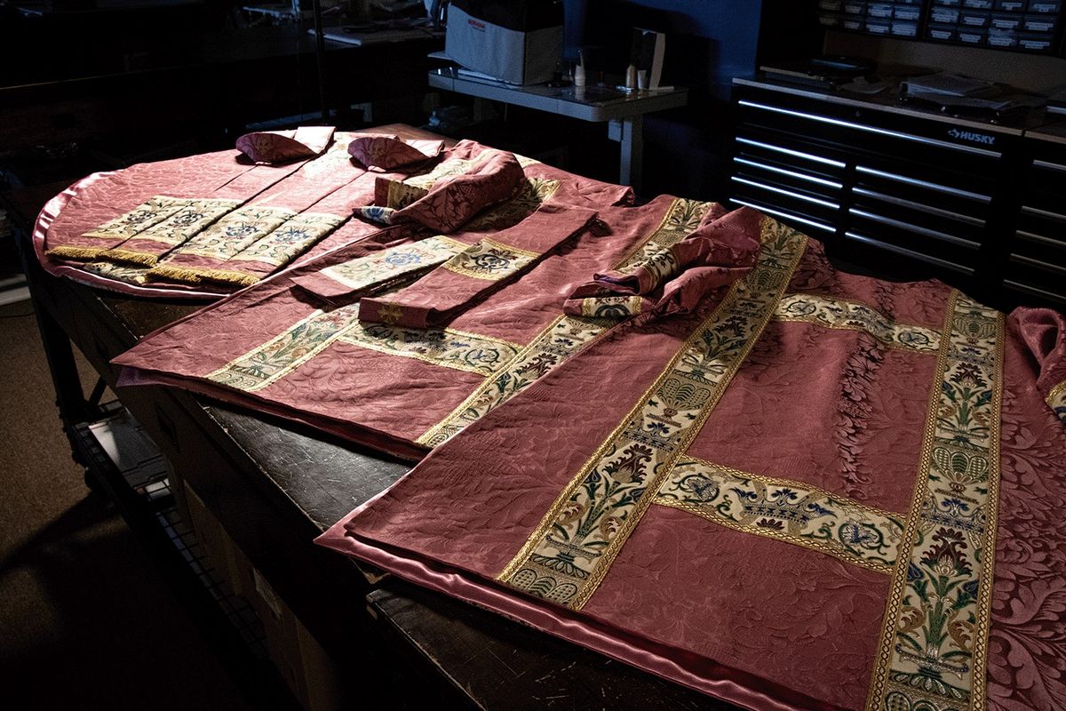 A rose vestment set with tapestry orphreys laid out on our workroom table