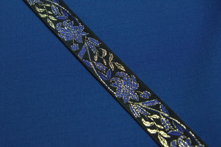 Close-up of black jacquard ribbon with royal blue flowers and metallic gold accents