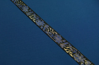 Royal blue gold and black floral jacquard trim displayed on black ecclesiastical brocade fabric