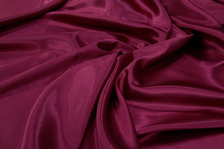 Cranberry Eminence Satin fabric smooth finish close up. Polyester Satin Bridal Fabric. Used for church vestment lining. 