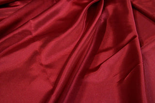 Red Eminence Satin fabric smooth finish close up. Polyester Satin Bridal Fabric. Used for church vestment lining. 