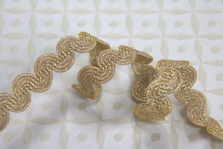 Close-up of textured metallic gold woven gimp braid trim with flexible curved construction