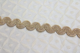 
Metallic gold gimp braid arranged in a curve on white ecclesiastical brocade fabric