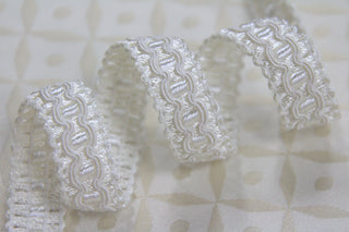 Close-up of 1/2 inch ivory woven gimp braid with raised decorative pattern