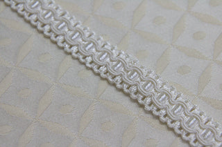 Close-up of 1/2 inch  ivory woven gimp braid with raised decorative pattern