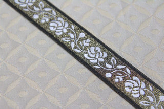 Close-up of white rose jacquard ribbon trim with gold metallic ground and black edging Full view