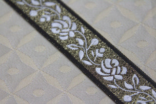 Close-up of white rose jacquard ribbon trim with gold metallic ground and black edging Detail