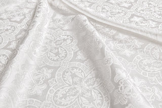 Chartres white brocade draped in soft folds, showing large floral quatrefoils and ornamental crosses.