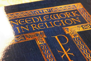Needlework in Religion: Close view of the gold cover title and Chi Rho symbol.