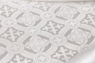 Close view of small crosses, four-petal rosettes and curved woven bands in Reims white brocade.