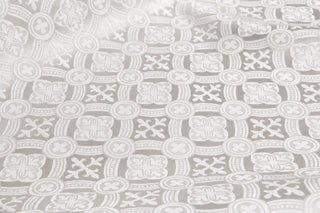 Reims white brocade showing rows of small ornamental crosses, quatrefoils and interlacing bands.