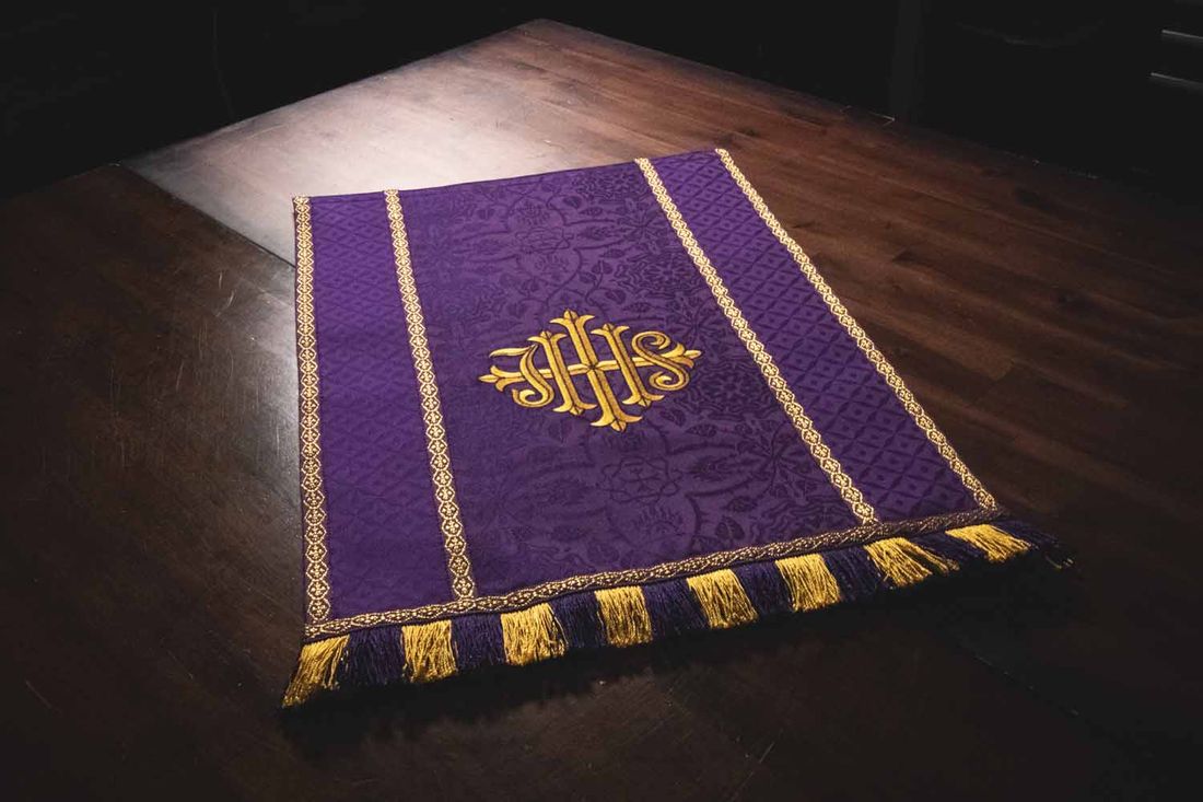 A violet hanging with a gold IHS between bands of gold galloon, finished with fringe