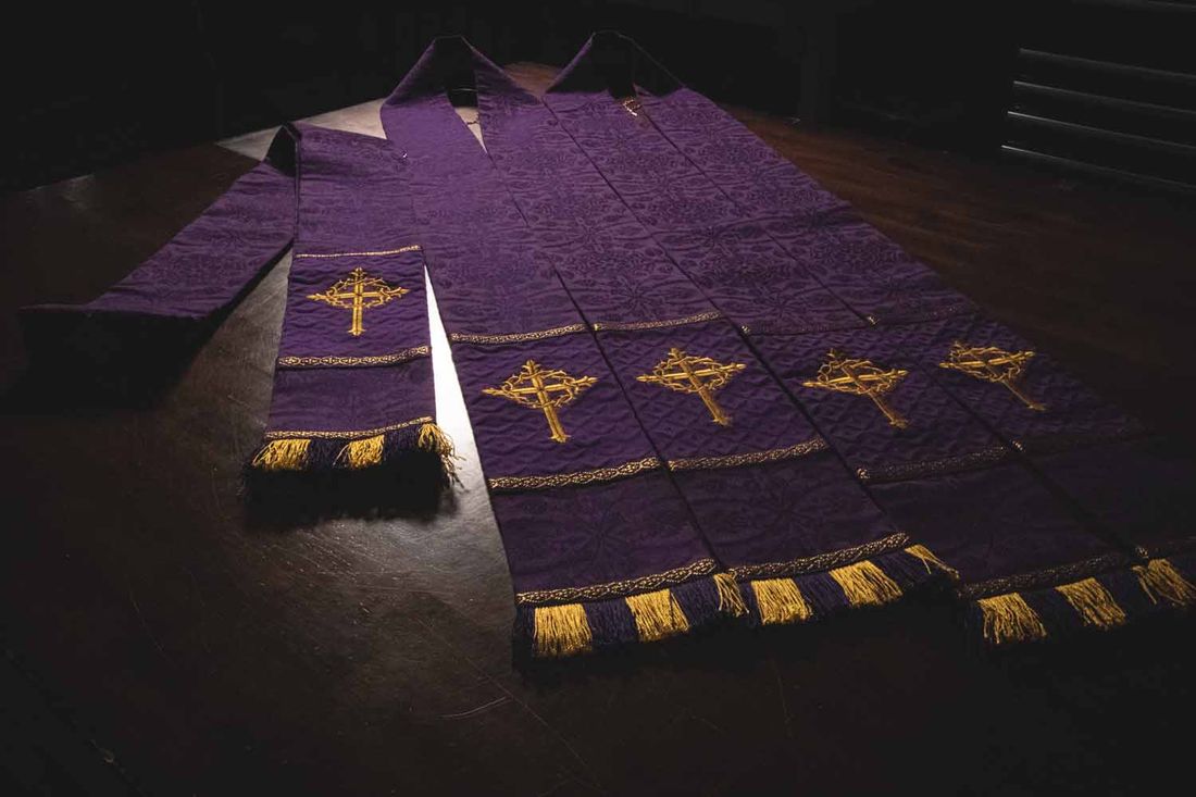 A row of violet stoles with gold crosses and tassels