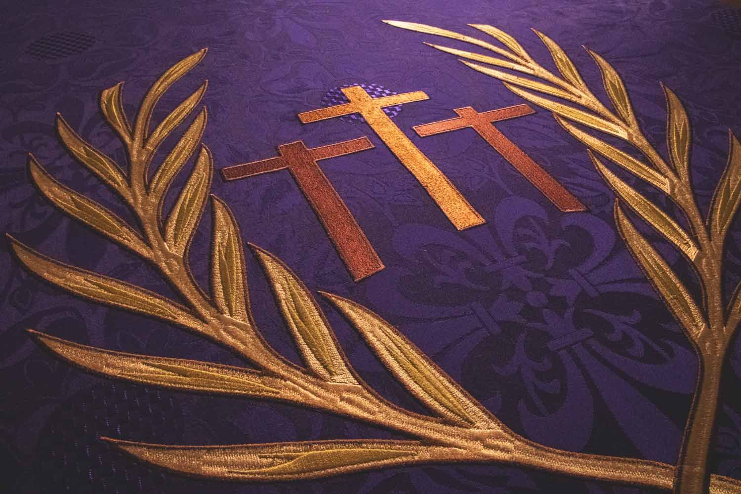 Gold palm branches and the three crosses of Calvary embroidered on violet brocade
