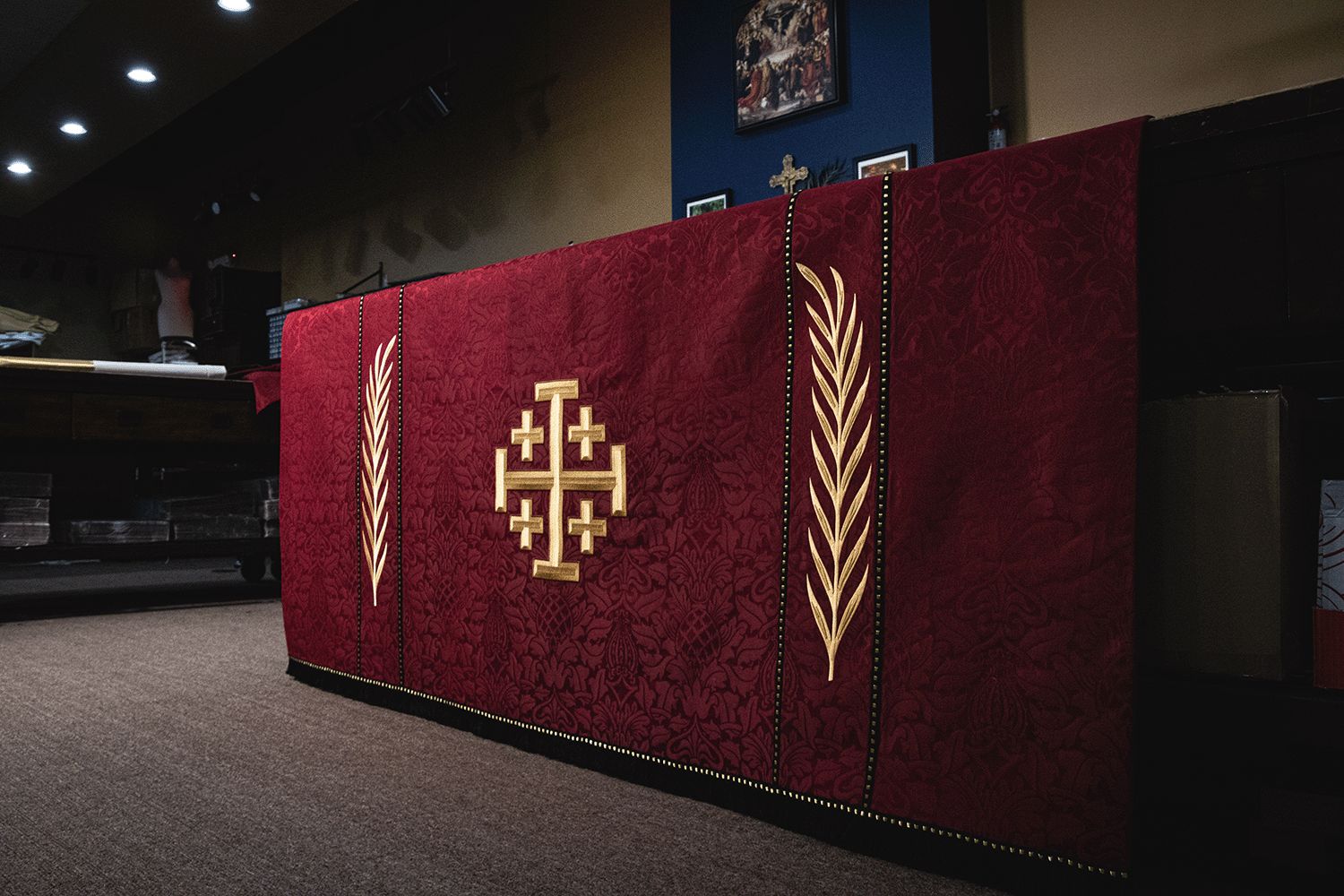 A red frontal with the Jerusalem cross between palm branches, on an altar in our workroom