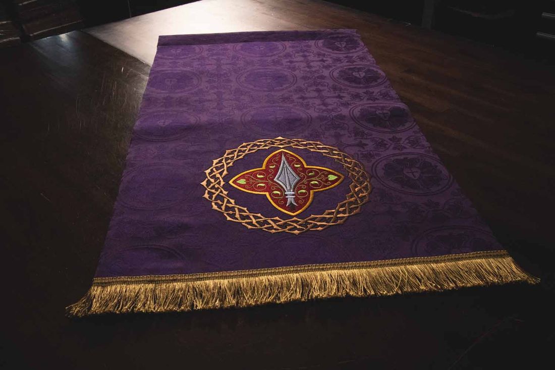 A violet hanging laid flat, with a spear point in a quatrefoil ringed with thorns