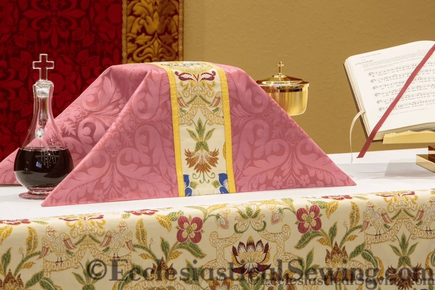 The rose chalice veil with a tapestry orphrey, over a chalice on an altar