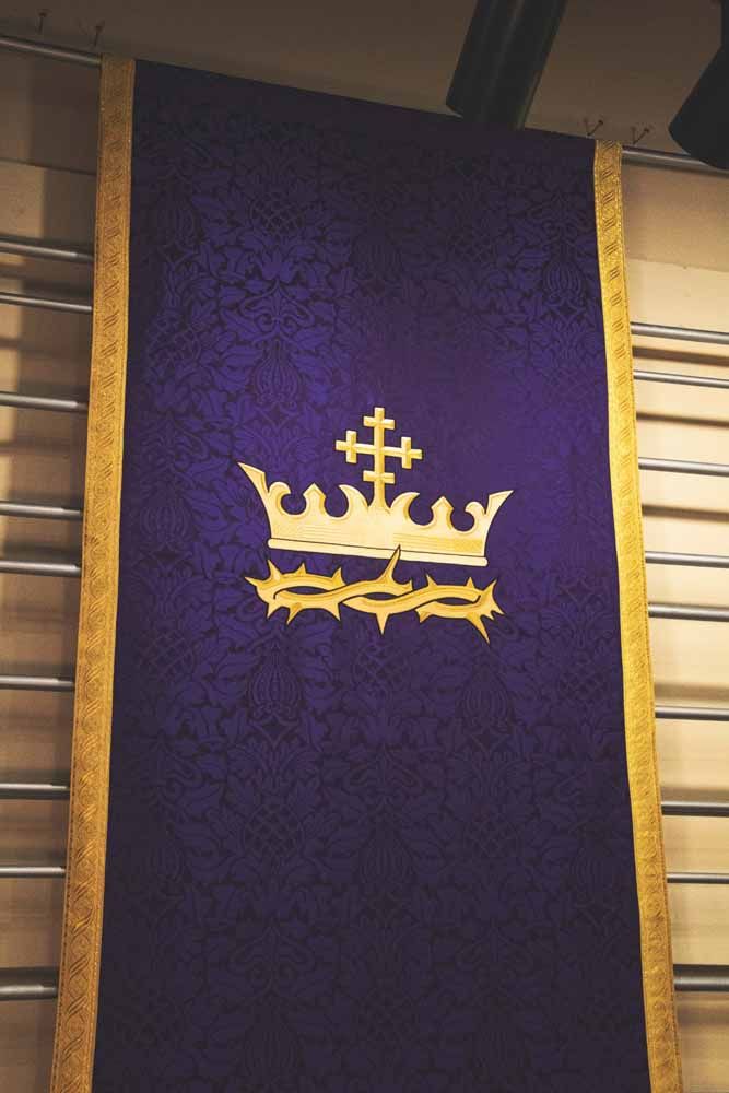 A violet hanging with a gold crown above a crown of thorns