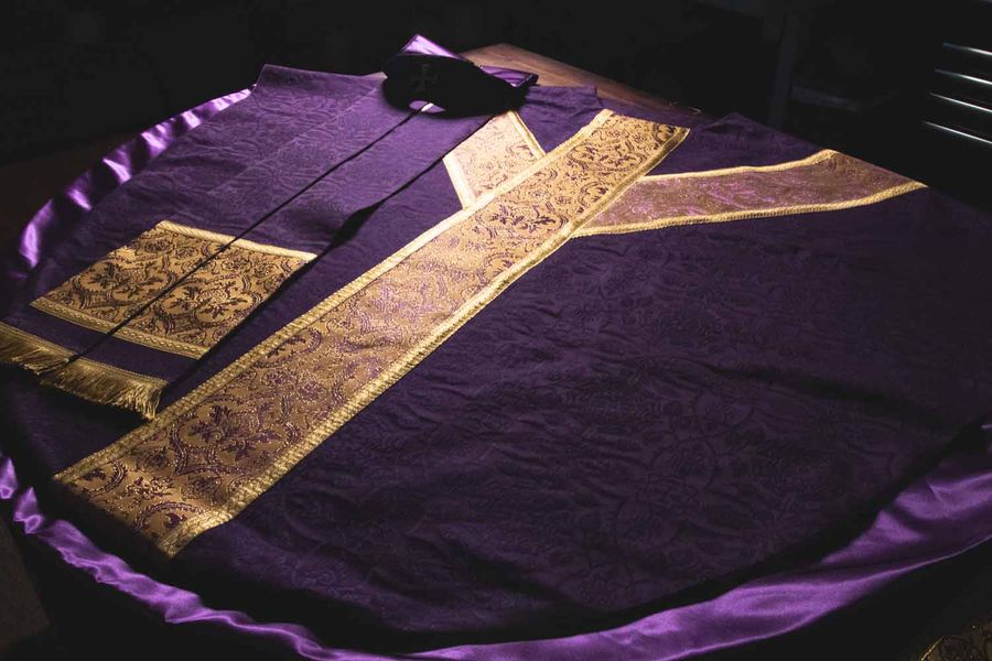 A violet chasuble laid flat with gold orphreys