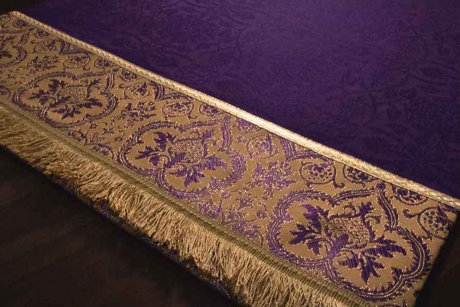 The gold tapestry border and fringe of a violet hanging