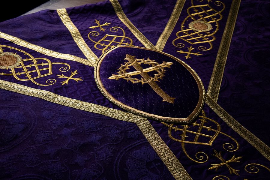 A cross wreathed in thorns in an oval on the yoke of a violet chasuble